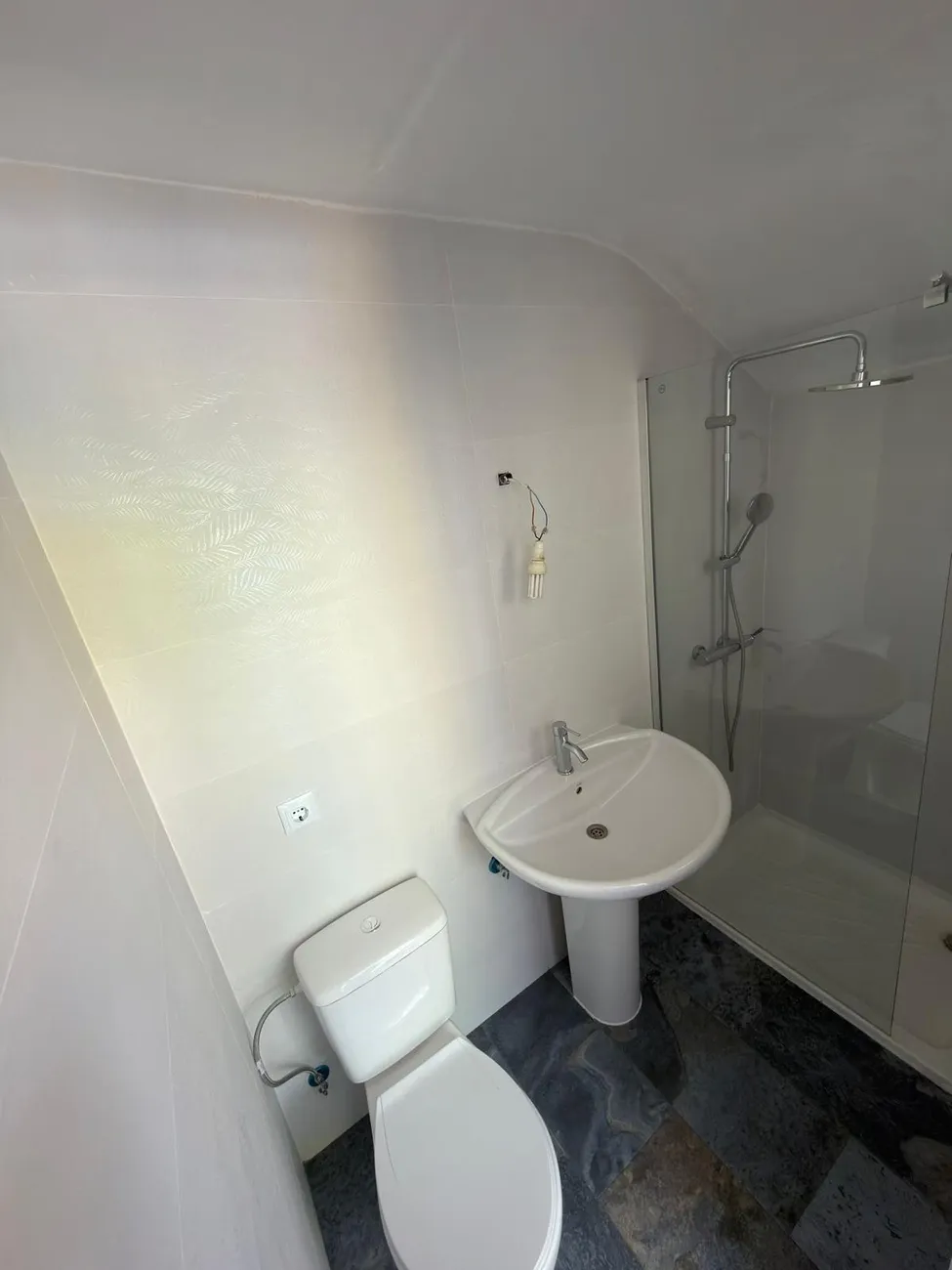 Baño completo reformado con plato de ducha, mampara y lavabo con pie