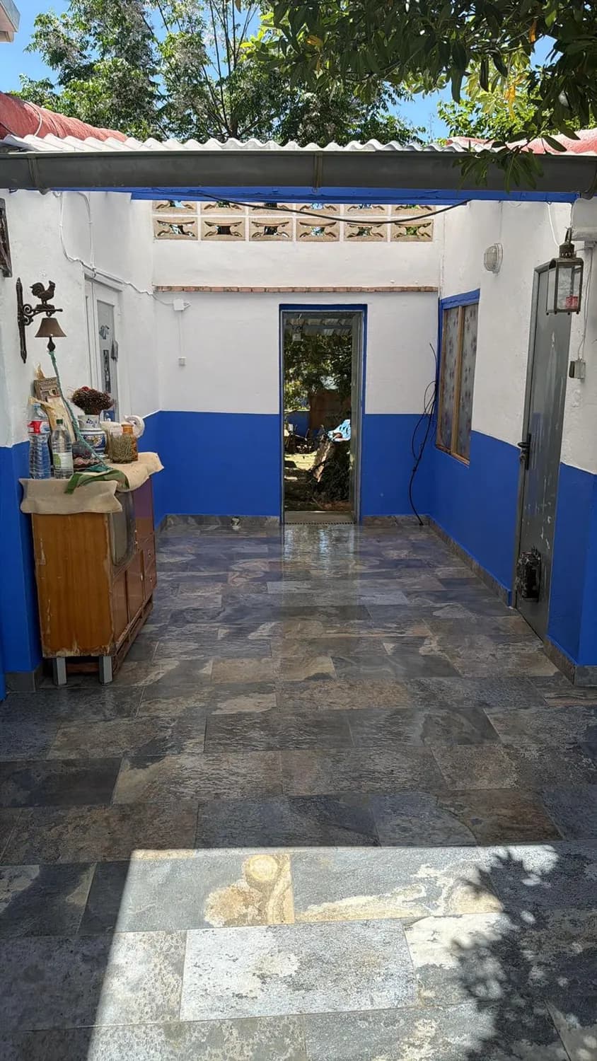 Patio cubierto reformado con solado de pizarra y paredes en blanco y azul